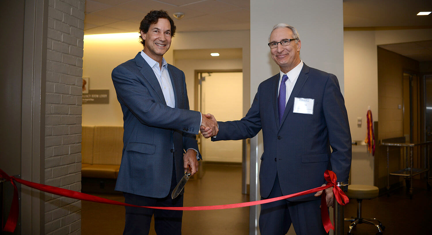Richard Lichter and Dean Andrew Hoffman shake hands before cutting the ribbon at the dedication of the Richard Lichter Emergency Room.