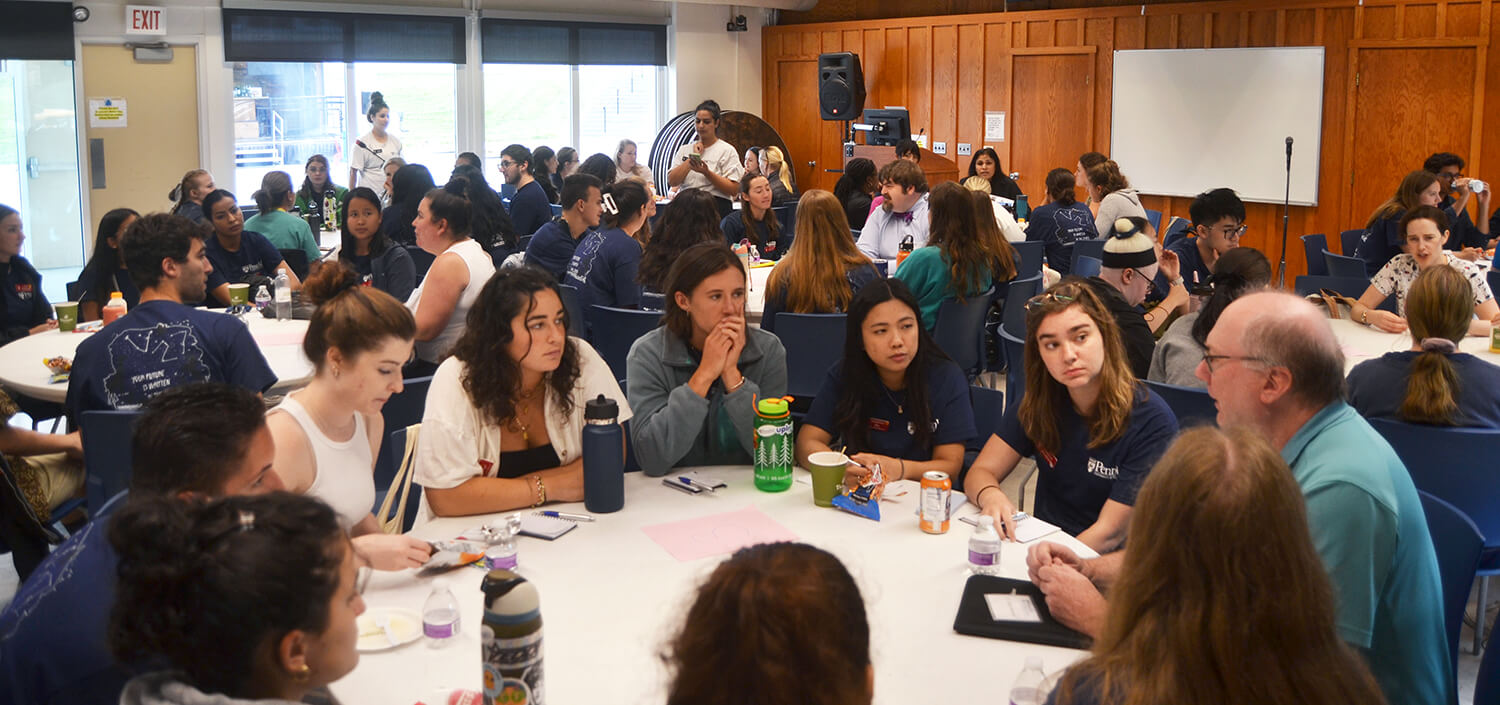 photo of students around table speaking with faculty member