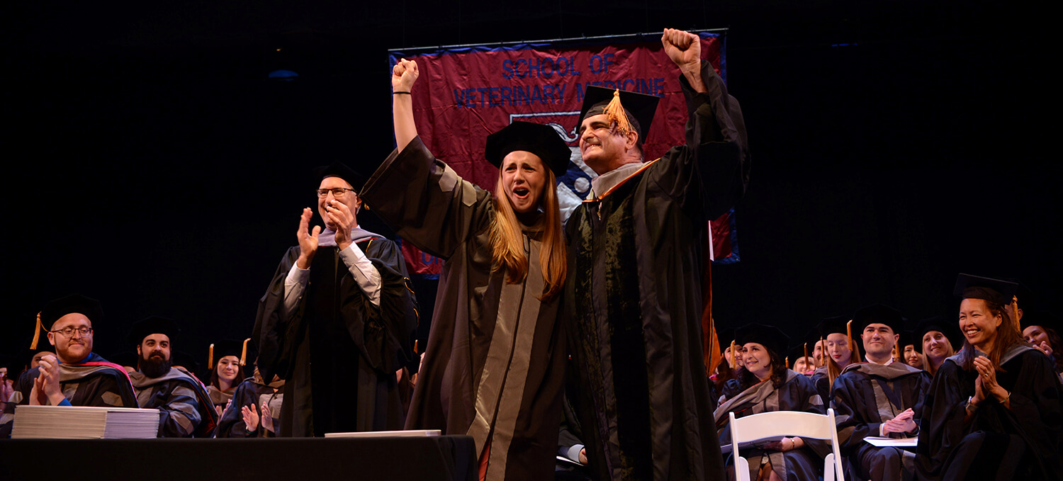 Photo of graduate and her father with arms raised in celebration