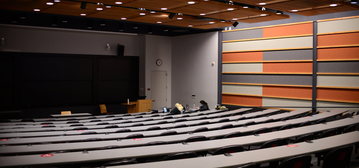 Two students study in a lecture hall that normally seats 130.