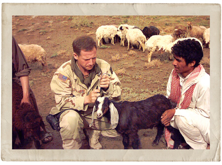 CPT Eric Lombardini examining a goat in Southern Iraq, OIF, 2004.