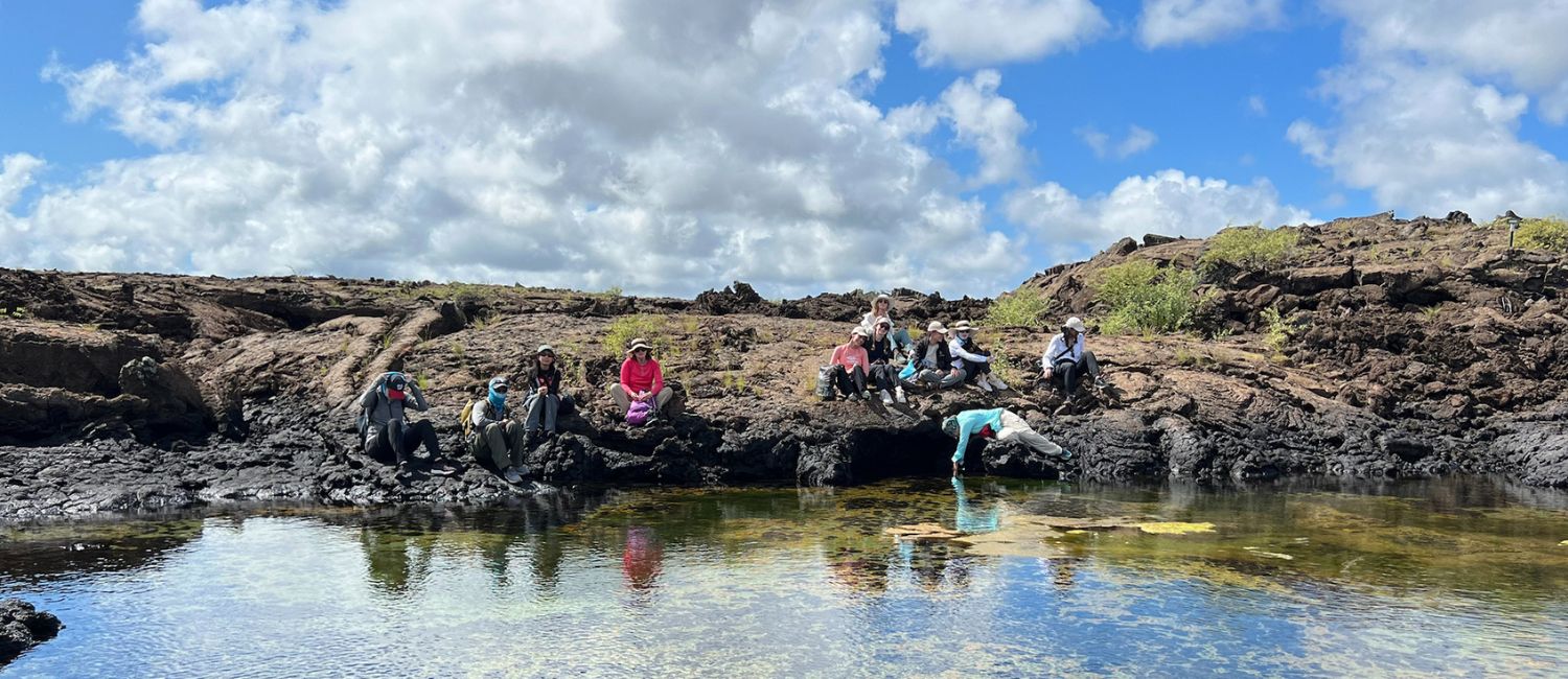 students studying the galapagos, sitting on waterfront