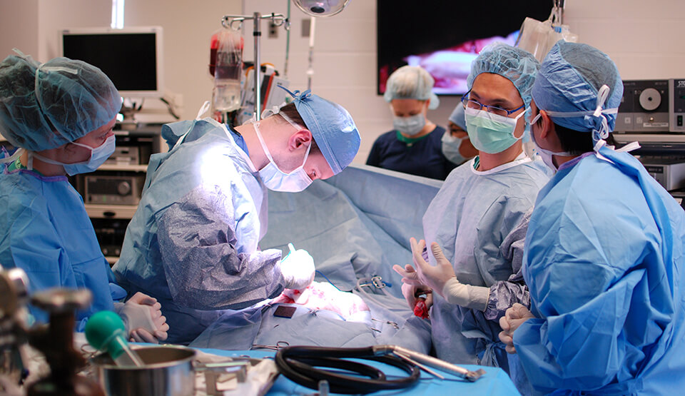 Dr. Micahel Mison, second from right, instructs a student, at right, during surgery. 