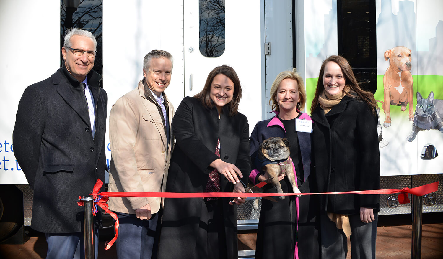 A celebratory ribbon-cutting ceremony marked the unveiling of the Shelter Medicine mobile clinic, a culmination of a vision that Watson (center) and colleagues dreamed up five years ago. Joining her in the festivities were, from left, Penn Vet Dean Andrew Hoffman, David Haworth of PetSmart Charities, Katy Champ of the Bernice Barbour Foundation (with Tupug the dog), and Reinhard.