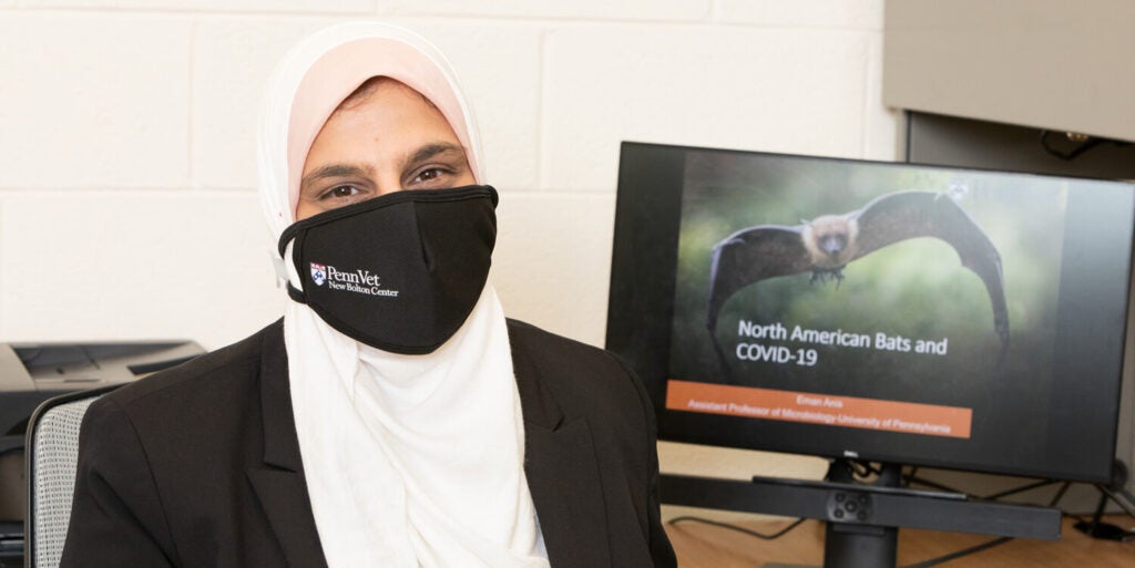 A person wearing a mask sitting at a desk.