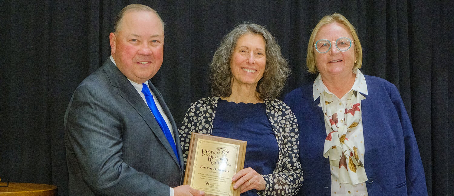 Three people standing with an award.
