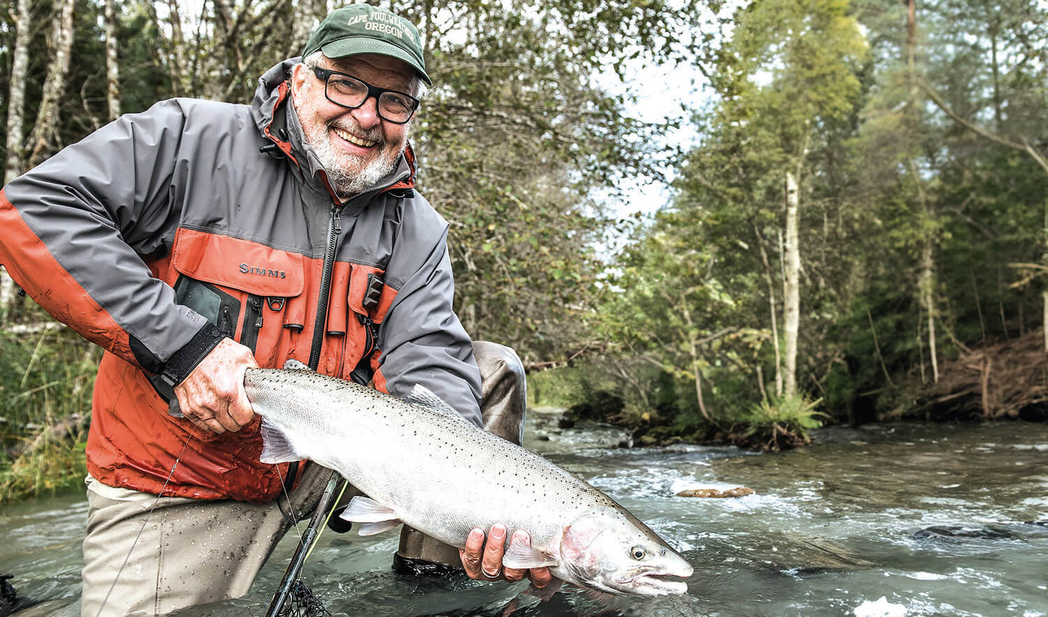 A person holding a fish in a stream.