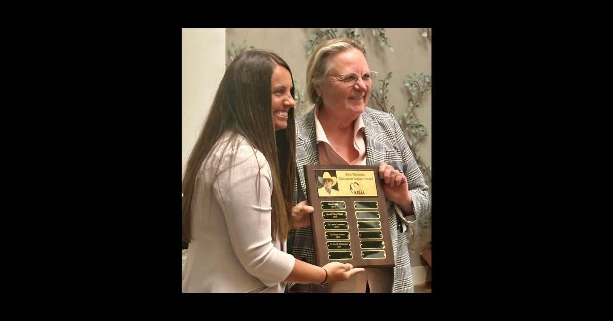 Two women holding an award.