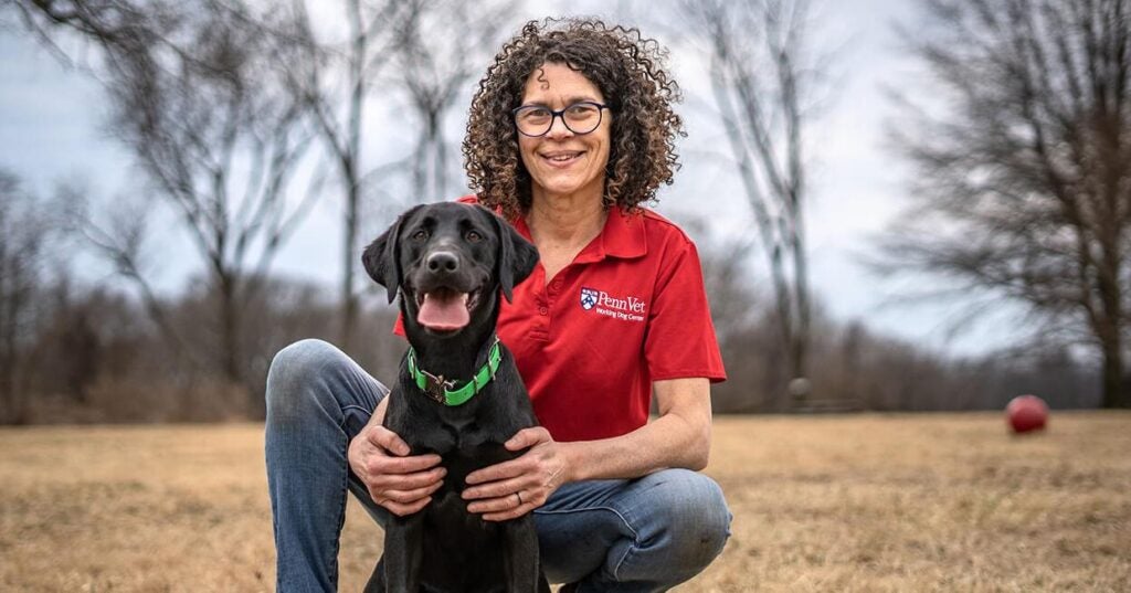 Woman sitting with a black lab.