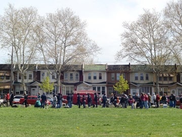 A large group of people standing in the grass in front of a row of houses.
