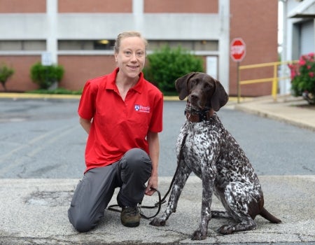A person in red shirt kneeling next to a dog