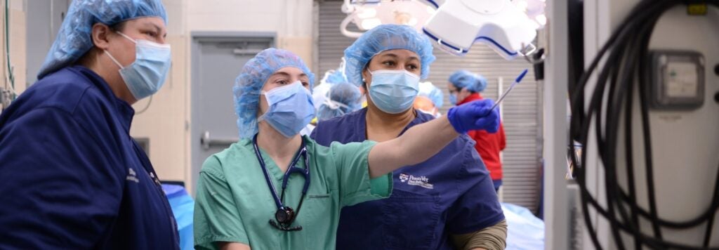 People in scrubs looking at a screen.
