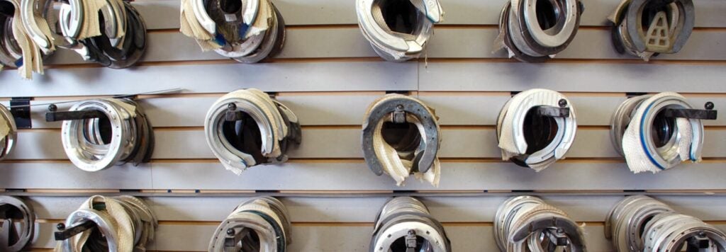 A row of horse shoes hanging on a wall.
