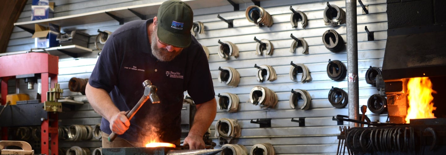 A person is working on a piece of metal in a shop.