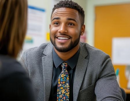 a person in a suit and tie sitting at a desk talking to another person