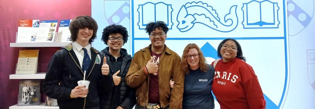 A group of young students standing for a photo in front of Penn Vet booth.