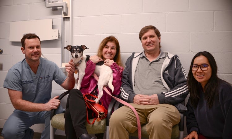 People sitting with a dog sitting on their lap.