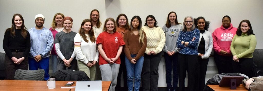 a group of people posing for a photo in a classroom