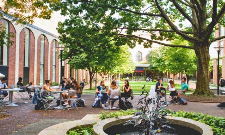 a group of people sitting around a fountain in a courtyard