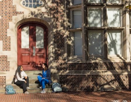 two individuals sitting on the steps of a building