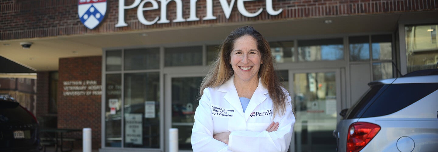 A person standing in front of the Penn Vet sign with a Car behind them.