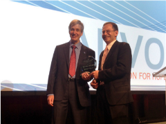 Two people in front of a screen at an awards ceremony