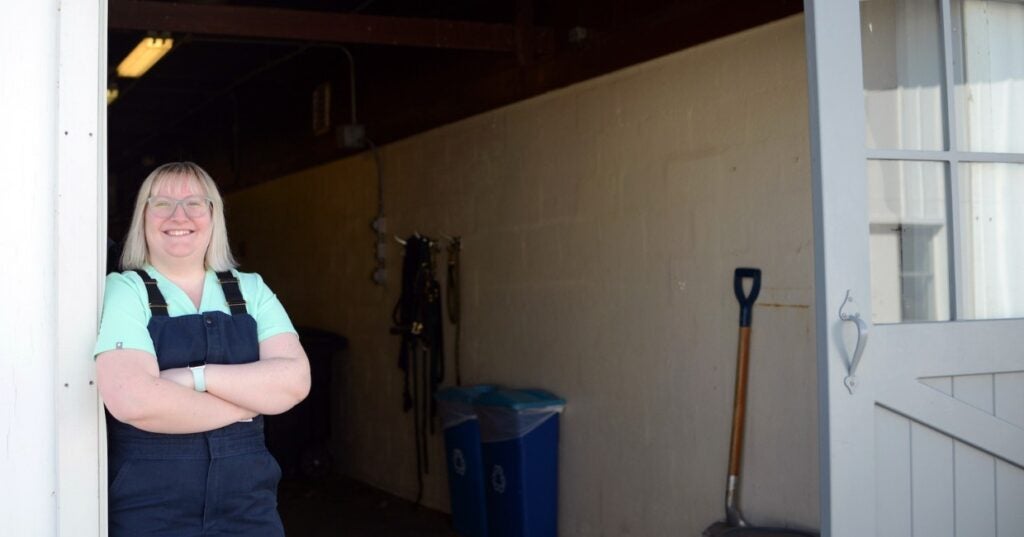 A person in overalls standing in front of a garage door.