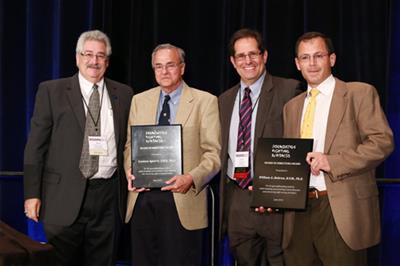 Four people standing with plaques.