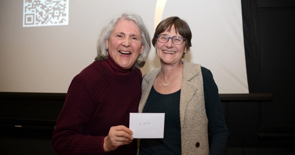 Two people holding up an envelope in front of a projector screen