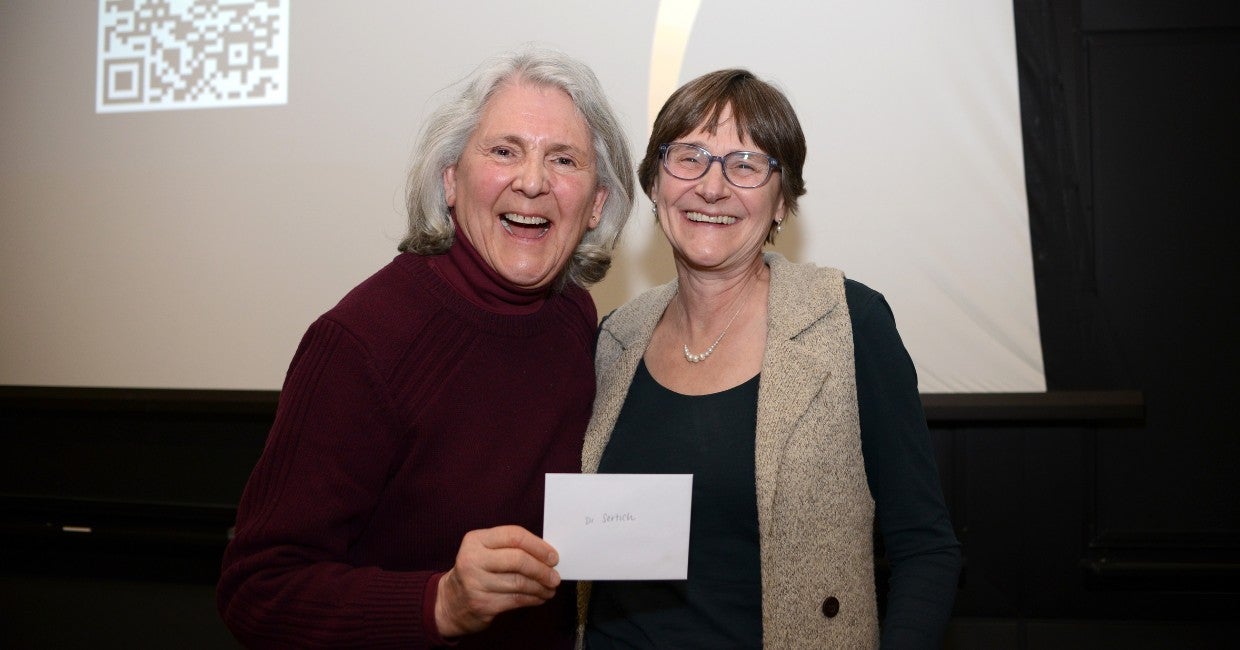 Two people holding up an envelope in front of a projector screen