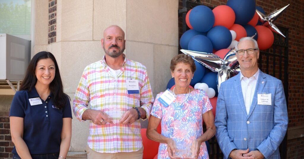 three people standing in front of a building with balloons