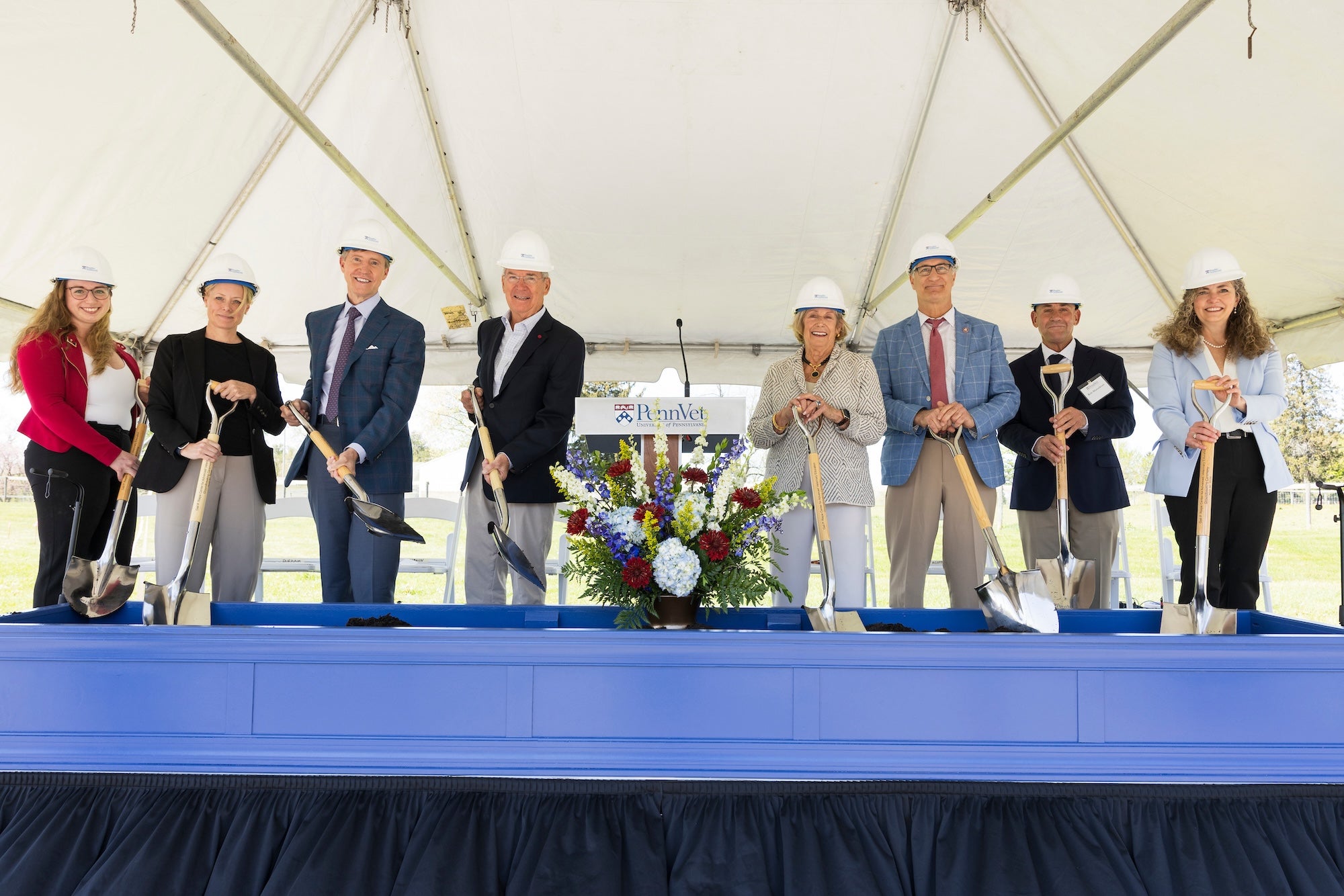 Eight people on stage with shovels for ceremonial groundbreaking