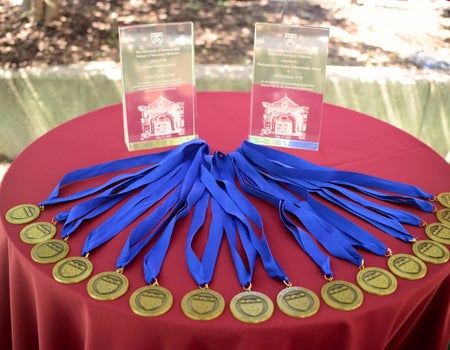 A table with a red table cloth and awards on it.