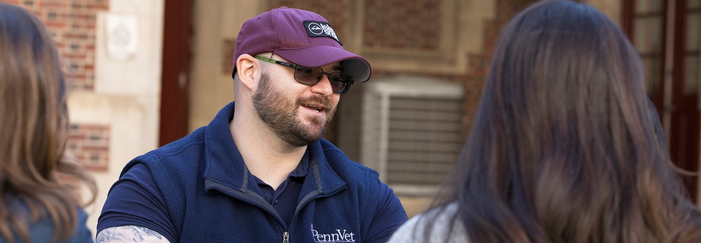 A person in a maroon hat sitting outside talking.