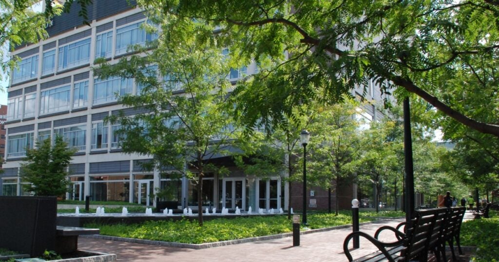 A building with glass with a brick walkway and bench.