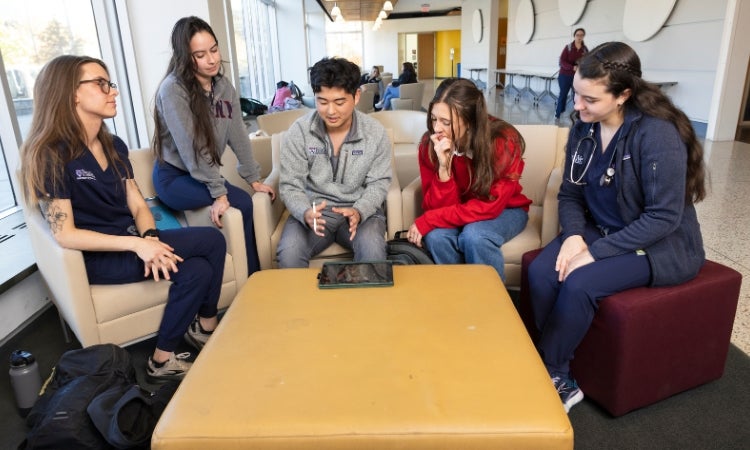 a group of people sitting around a table looking at a tablet