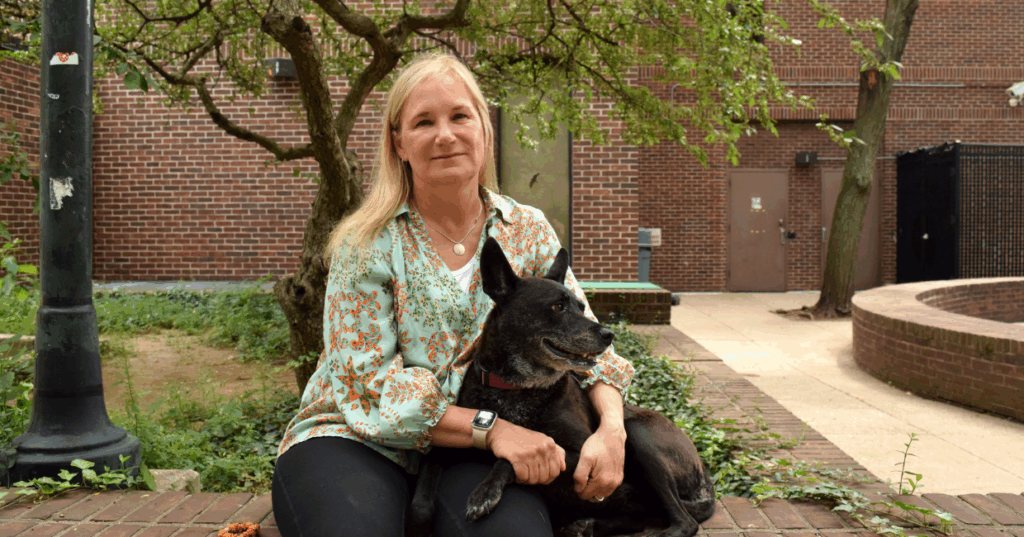 A person sitting on a brick wall with their dog