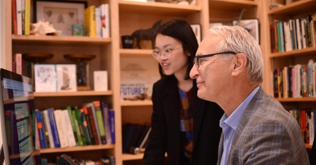 Two people in front of a computer reviewing a webpage.
