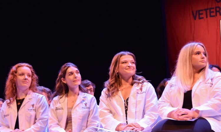 students in white coats looking at a speaker