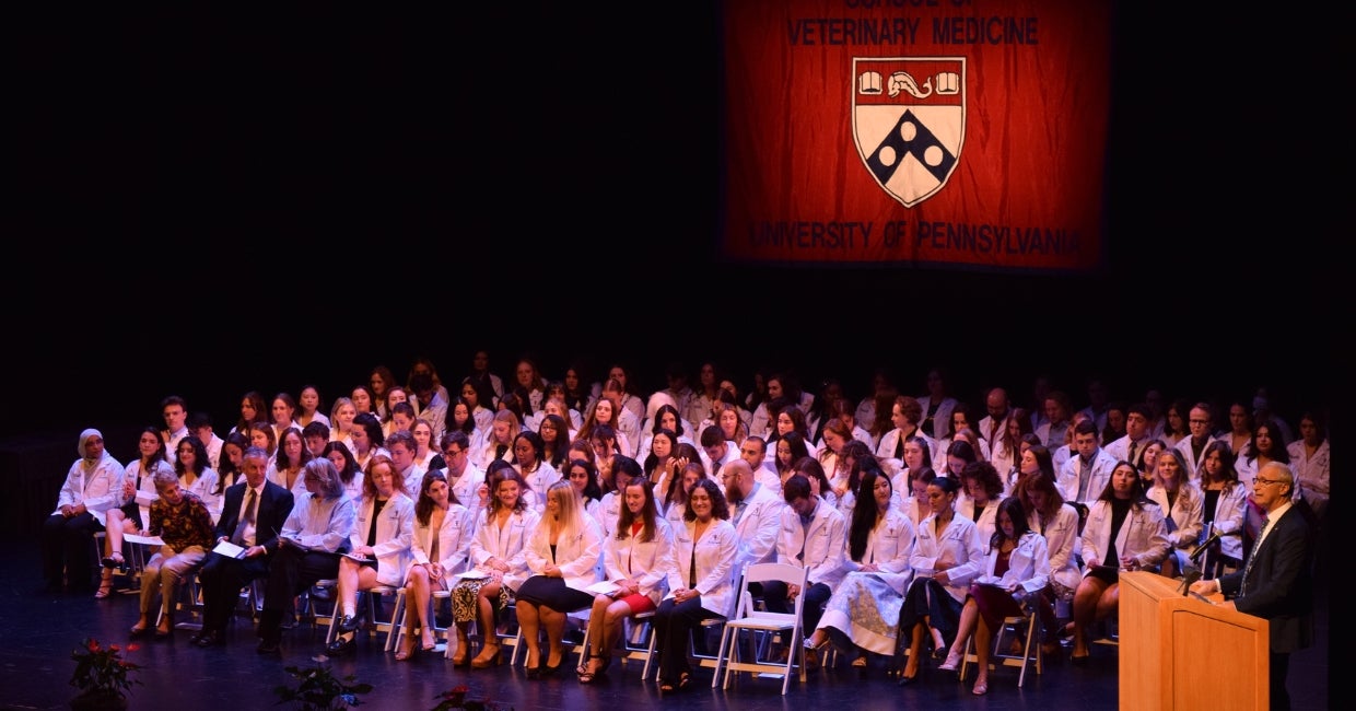 A large group of people sitting in front of a stage