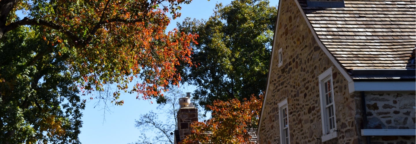 Fall foliage next in front of a stone building.