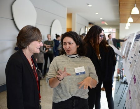 Two people talking to each other in front of a poster.
