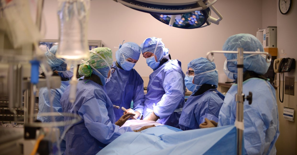 People in blue scrubs in an operating room.