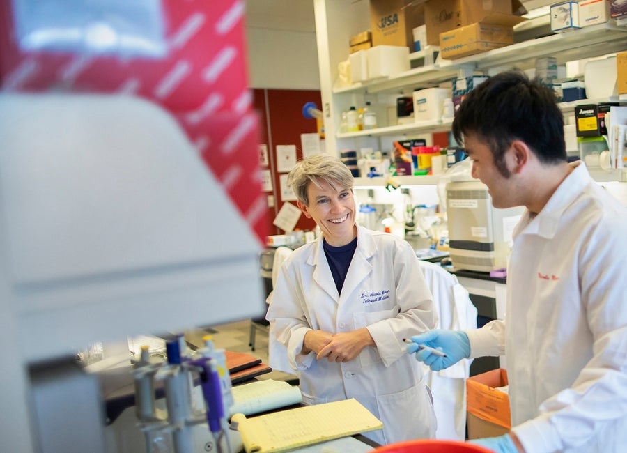 Two people in lab coats in a research lab talking
